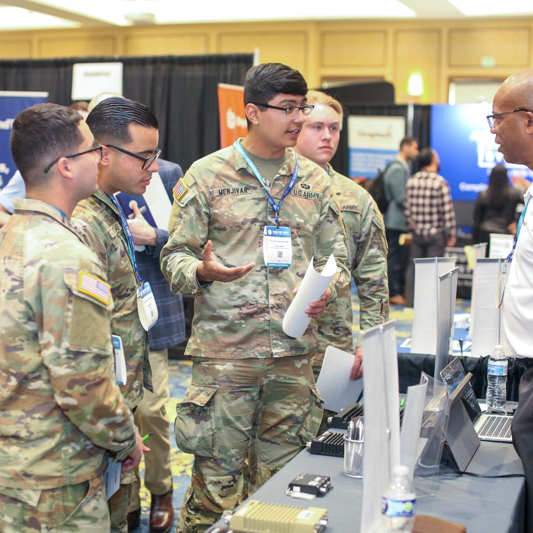 Soldiers and civilian industry representatives in conversation at an exhibit table during a chapter TechNet event